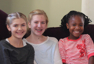 Three young girls smile together as therapeutic foster child enjoys family