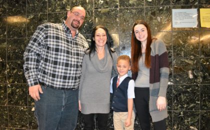 A young boy in cute vest at court to finalize his adoption with new parents and new older sister